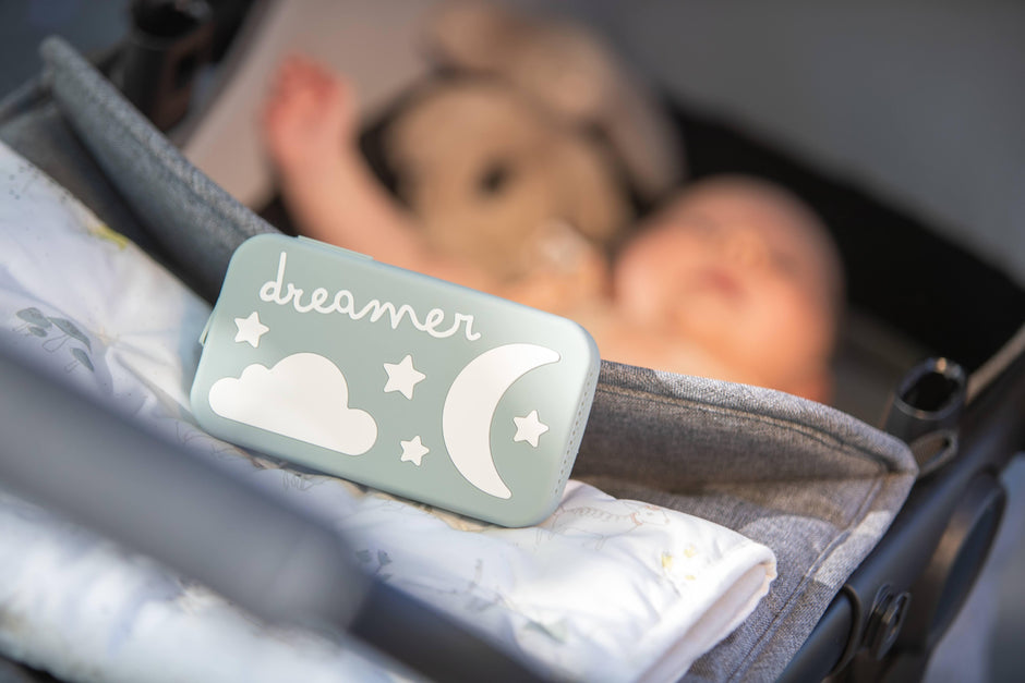Dreamer baby sound machine on stroller with baby out of focus in the background (Sage-Dreamer)