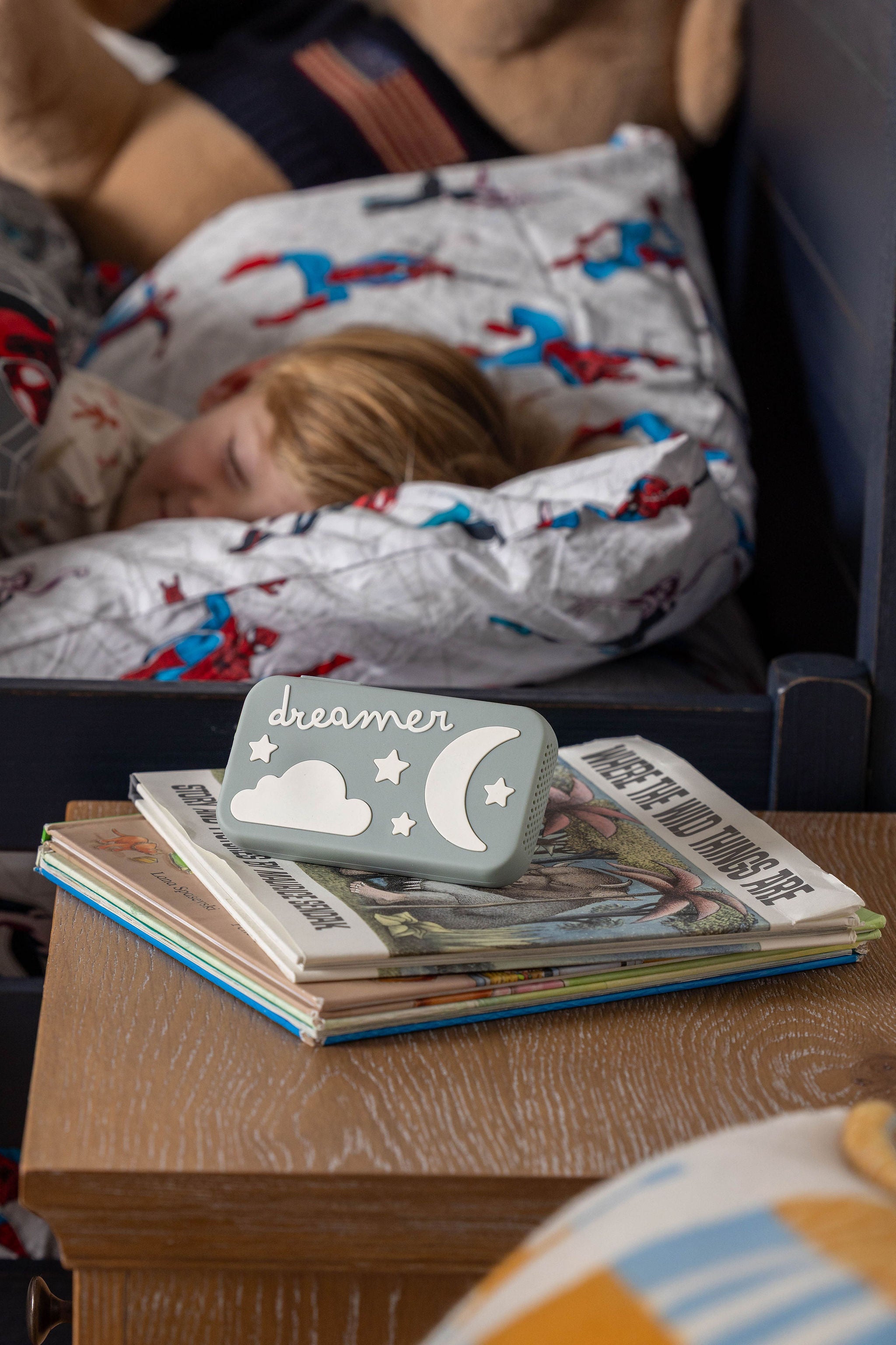 Child sleeping under a blanket with a Dreamer on top of books